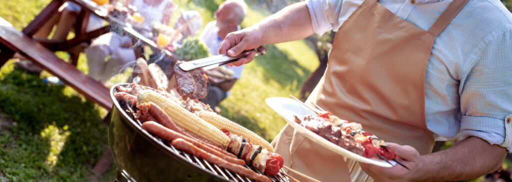 Barbecue en extérieur avec grillades de viande, légumes et maïs en cuisson